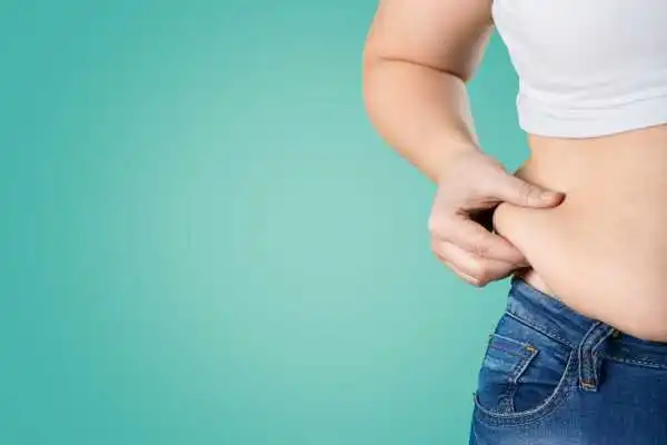 Image of woman pinching her love handles to show weight gain Malmesbury